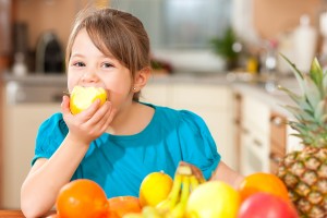 Healthy eating - child eating an apple, lots of fresh fruit on t