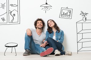 Portrait Of Happy Young Couple Sitting On Floor Looking Up While