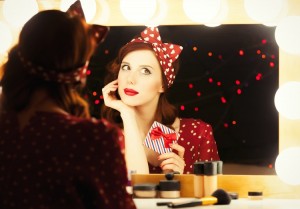 Portrait of a beautiful surprised woman with present box near a mirror. Photo in retro color style.