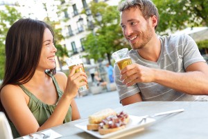Couple eating tapas drinking beer in Madrid, Spain. Romantic man and woman enjoying local traditional food on square in Madrid. Asian woman and Caucasian man dating.