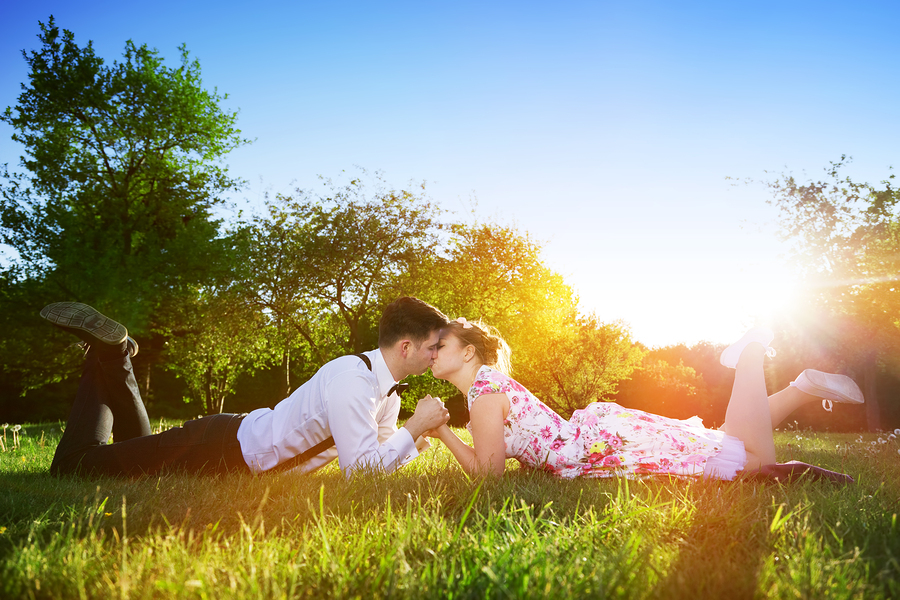 Romantic couple in love kissing while lying on grass in spring p