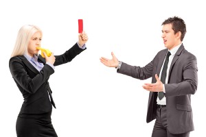 Woman in business suit showing a red card and blowing a whistle