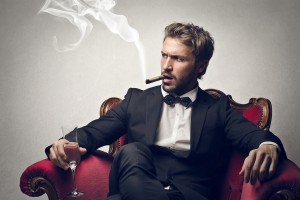 handsome boss sitting on the armchair smokes cigar