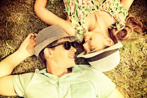 Happy young couple relaxing on the lawn in a summer park. Love c