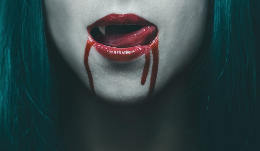 Sensual female vampire lips in blood close-up image. Halloween or horror theme