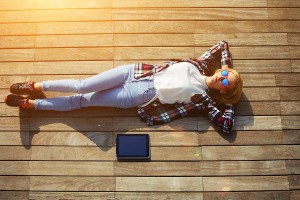 Active young tourist lying on a wooden floor with a tablet enjoy