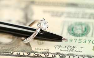 Wedding ring on pen, on banknotes background. Marriage of conven