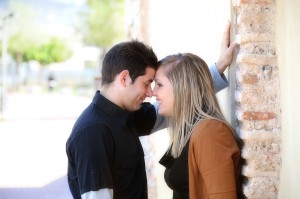 Young Couple Flirting Against A Brick Wall In A Park