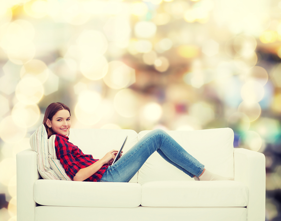 technology and happy people concept - teenage girl sitting on so