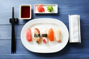 Sushi rolls on plate, soy sauce and chopsticks on color wooden b