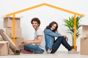 Smiling Young Couple Sitting Back To Back After Moving House