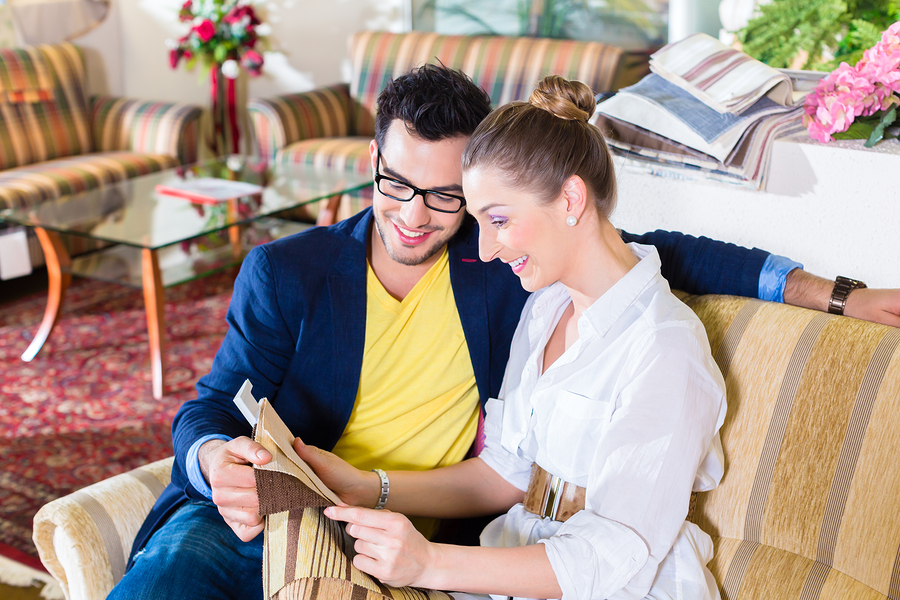 Young couple selecting together seat cover for sofa in furniture