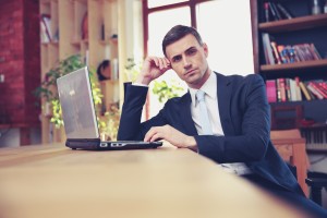 Confident businessman sitting with laptop at office