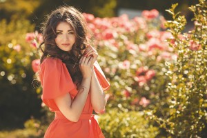 Beautiful woman in a summer garden blossoming roses.