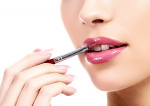 beautiful young woman applying lips makeup with cosmetic brush