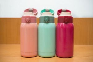 three colorful thermos on a wooden table