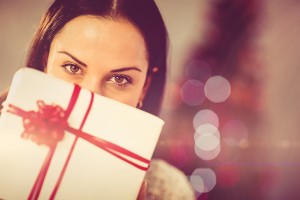 Pretty brunette holding christmas present at home in the living